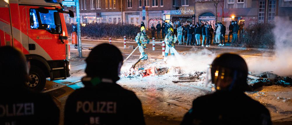 Einsatz nur mit Polizeischutz: Feuerwehrleute löschen eine Barrikade an der Ecke Kottbusser Damm/Sanderstraße in der Nacht des Jahreswechsels. 