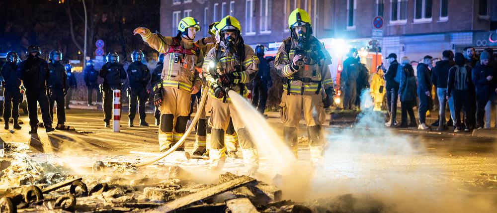 Feuerwehrleute löschen in der Silvesternacht eine der zahlreichen errichteten Barrikaden auf Berliner Straßen. 