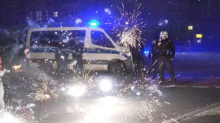 Polizeibeamte stehen hinter explodierendem Feuerwerk. An Silvester kam es in Berlin zu heftigen Ausschreitungen. (Archivbild)