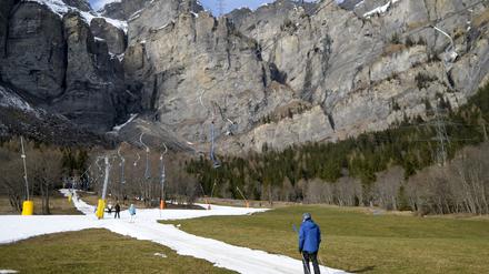 Skifahrer benutzen einen Lift auf einer künstlich beschneiten Skipiste in der Schweiz.
