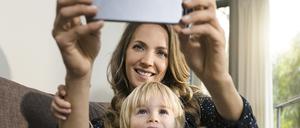 Smiling mother with son taking a selfie on sofa at home