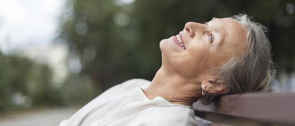 Eine ältere Frau lächelt dem Himmel entgegen. (Symbolbild)