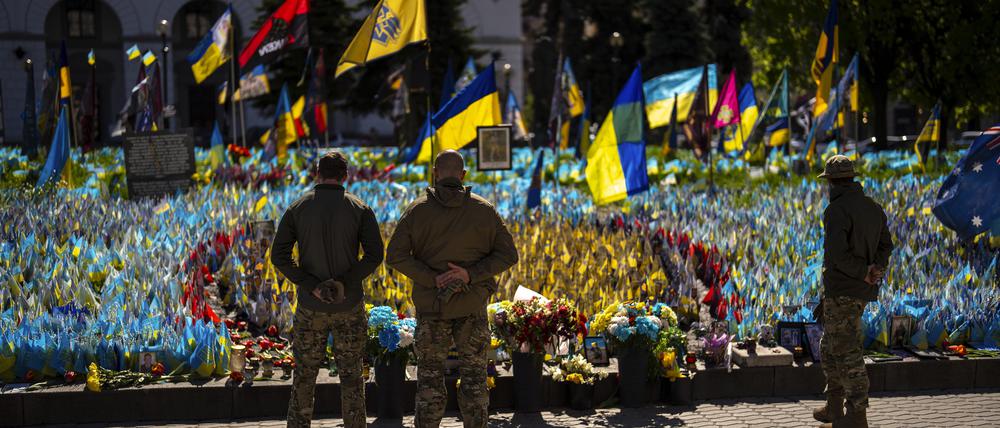 Ukrainische Soldaten stehen auf dem Unabhängigkeitsplatz im Zentrum von Kiew neben ukrainischen Flaggen und Fotos, die zum Gedenken an im Krieg gefallene Zivilisten und Soldaten aufgestellt wurden. 