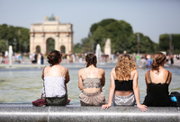 Vier Frauen sitzen bei heißen Temperaturen am Louvre auf dem Beckenrand eines Springbrunnens