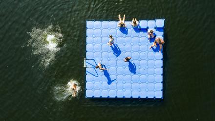 Schön, aber nicht ungefährlich: Menschen springen im Altwarmbüchener See von einer Badeinsel (Archivaufnahme).