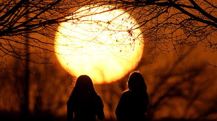 Menschen beobachten den Sonnenuntergang in einem Park an einem ungewöhnlich warmen Tag in Kansas City. Eine Warmfront sorgt für frühlingshaftes Wetter in weiten Teilen des Landes in einem Monat, der normalerweise zu den kältesten Monaten des Jahres gehört. 