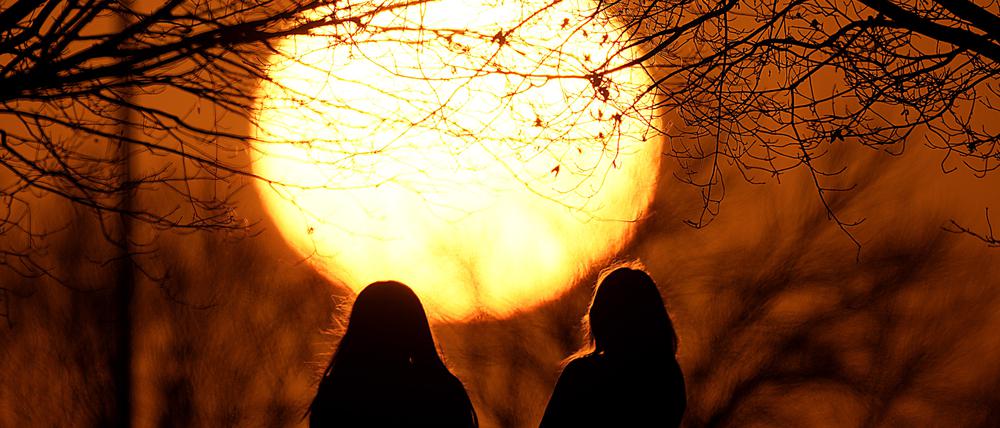 Menschen beobachten den Sonnenuntergang in einem Park an einem ungewöhnlich warmen Tag in Kansas City. Eine Warmfront sorgt für frühlingshaftes Wetter in weiten Teilen des Landes in einem Monat, der normalerweise zu den kältesten Monaten des Jahres gehört. 