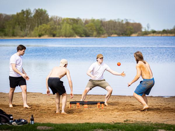 In Isernhagen in Niedersachen spielen junge Männer am Rande vom Hufeisensee „Spikeball“ in der Sonne. 