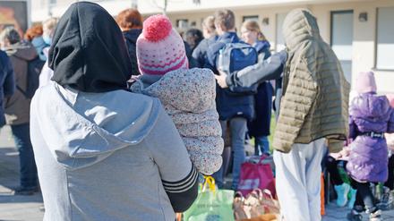 Geflüchtete aus der Ukraine stehen mit ihrem Gepäck vor den Gebäuden eines Flüchtlingsheims in Köln Worringen. 