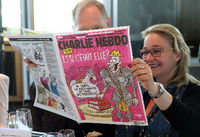 Gäste blättern in einer Ausgabe con "Charlie Hebdo".