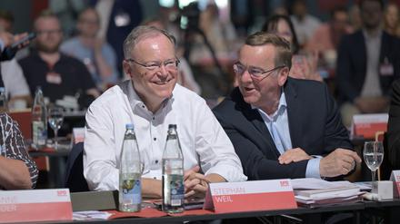 Boris Pistorius (r; SPD), Bundesverteidigungsminister, und Stephan Weil (SPD), Ministerpräsident von Niedersachsen, sitzen während des Parteitags in einer Halle und unterhalten sich.