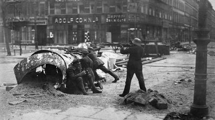 Hinter einer umgestürzten Litfaßsäule in Berlin gehen im März 1919 Soldaten der Regierungstruppen in Stellung.