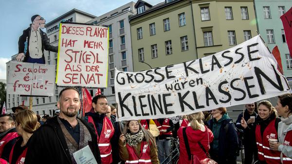 Mit Plakaten und Transparenten stehen Teilnehmer an einer Demonstration zum Auftakt eines ganztägigen Warnstreiks an Berliner Schulen am Moritzplatz. (Archivfoto)