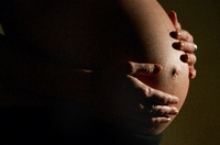 Eine hochschwangere Frau fasst sich mit beiden Händen an ihren Bauch (Archivfoto).
