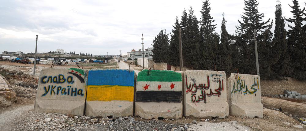 Die syrische und ukrainische Flagge auf Steinen im Norden von Aleppo, Syrien.