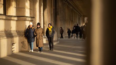 Three tourist ladies walk through a passage in Berlin during a cold winter day