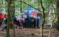 Polizisten und Notärzte bringen einen Journalisten zu einem Krankenwagen, der von einer Hängebrücke im Hambacher Forst gefallen ist.