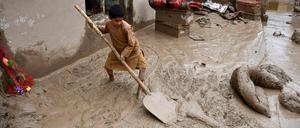Ein afghanischer Junge schaufelt Schlamm aus dem Hof eines Hauses, nachdem es in einem Dorf im Bezirk Baghlan-e-Markazi in der Provinz Baghlan am 11. Mai 2024 zu heftigen Überschwemmungen gekommen war. 