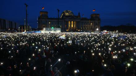 Teilnehmer leuchten mit ihren Handys während einer Demonstration gegen Rassismus und rechtsextreme Politik vor dem Reichstagsgebäude in Berlin.