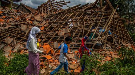 Bewohner laufen nach dem Erdbeben an den Ruinen eines Hauses vorbei. 