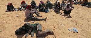Migranten aus afrikanischen Ländern südlich der Sahara sitzen am 16. Juli 2023 in einem unbewohnten Gebiet nahe der libyschen Grenzstadt Al-Assah.