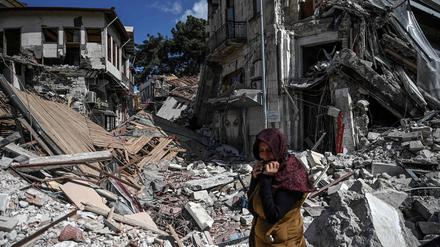 Eine Frau steht vor den Trümmern eines Hauses in Hatay. 