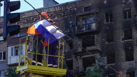 Ein Arbeiter befestigt eine russische Flagge in Mariupol.