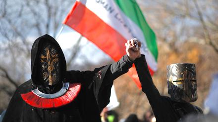 Protestierende im Iran stehen vor der iranischen Flagge.