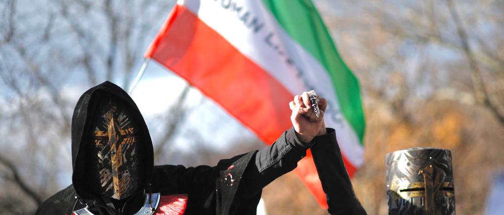 Protestierende im Iran stehen vor der iranischen Flagge.
