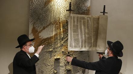 Rabbiner Elias Dray (l) schaut zu Rabbiner Shaul Nekrich, der die historische Sulzbacher Torarolle von 1792 hochhält, nachdem er sie während einer Zeremonie zum 76. Jahrestag der Befreiung des deutschen Vernichtungslagers Auschwitz am Internationalen Holocaust-Gedenktag in einem Andachtsraum auf dem Gelände des Bundestags vervollständigt hat.