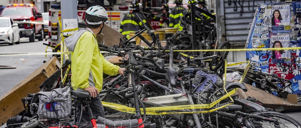 Ein Radfahrer hält an, um einen Stapel von E-Bikes nach einem Brand in Chinatown in New York zu betrachten.