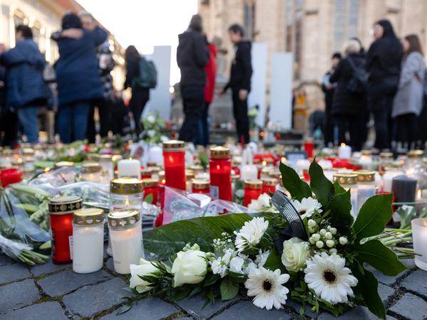 Menschen trauern mit Blumen und Kerzen bei einer Gedenkveranstaltung in Mühlhausen um die Verstorbenen.
