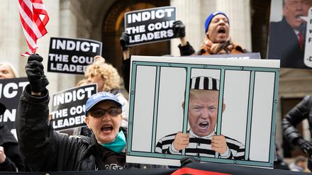 Archivbild: Demonstranten in New York halten Schilder mit einem Bild von Donald Trump im Gefängnis und Schildern mit der Aufschrift „Anklage gegen die Verantwortlichen des Gerichts“ in die Höhe.