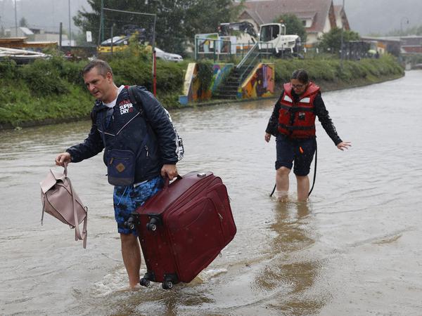Touristen waten in Leibnitz in Österreich nach dem Verlassen ihrer Unterkünfte auf einer überfluteten Straße durch das Hochwasser.