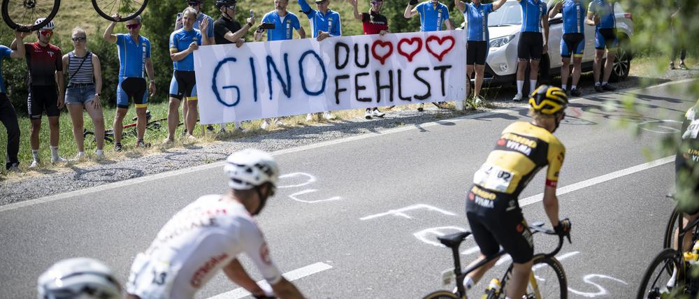 Das Fahrerfeld fährt an Fans vorbei, die dem nach einem Sturz verstorbenen Schweizer Gino Mäder gedenken.