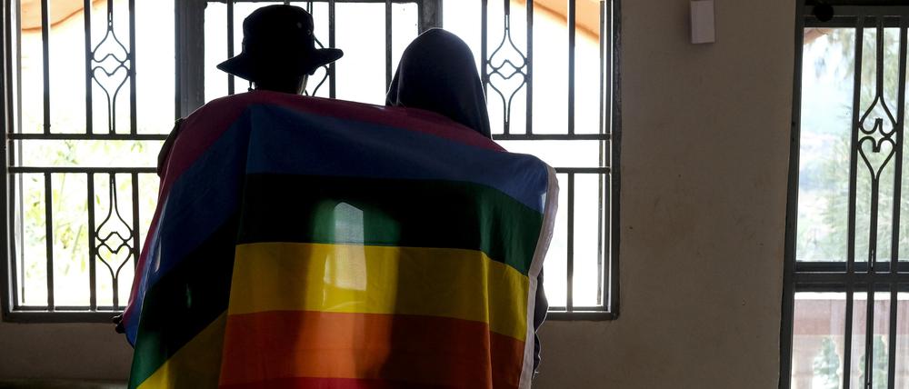 Ein Paar bedeckt sich mit einer Pride-Fahne. In Uganda hat das Verfassungsgericht ein umstrittenes Gesetz gegen Homosexuelle bestätigt.