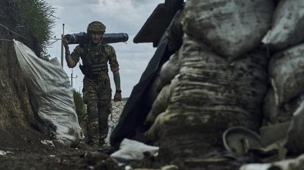 Ein ukrainischer Soldat trägt Vorräte in einem Graben an der Frontlinie bei Bachmut.