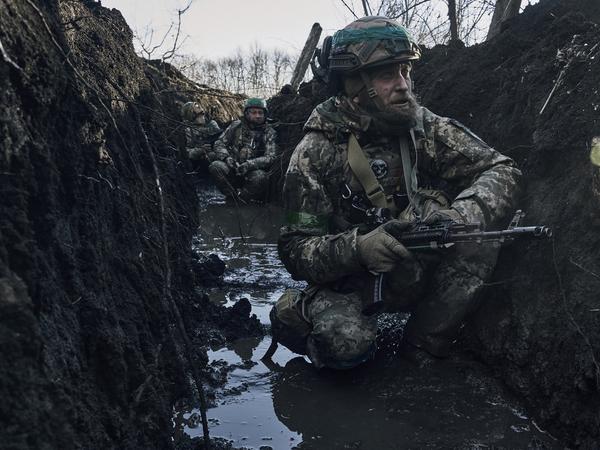 Ukrainische Soldaten hocken im Schlamm in einem Schützengraben unter russischem Beschuss an der Frontlinie in der Nähe von Bachmut.