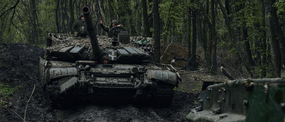 Ukrainische Soldaten winken auf einem vorbeifahrenden Panzer an der Frontlinie in Bachmut. 