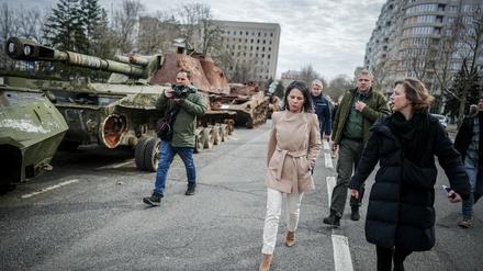 Annalena Baerbock geht bei ihrem Besuch des ehemaligen Sitz der Regionalverwaltung der Oblast Mykolajiw an zerstörten russischen Panzern vorbei. 