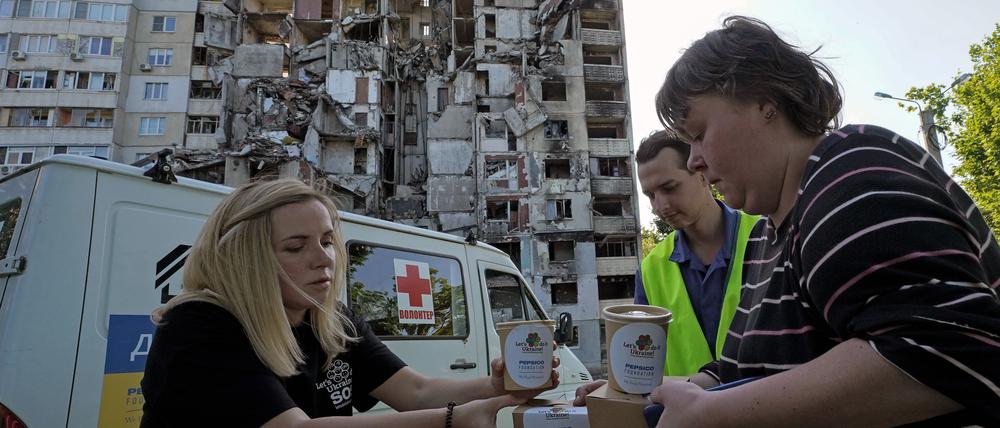 Charkiw: Anwohner erhalten vor ihrem Wohnhaus, das durch einen russischen Raketenangriff beschädigt wurde, kostenlose Mahlzeiten von Freiwilligen.