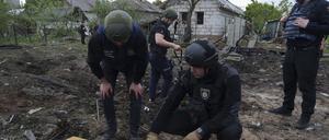 Ein ukrainischer Polizeibeamter und ein Staatsanwalt für Kriegsverbrechen inspizieren Bruchstücke einer Gleitbombe vor einem beschädigten Haus nach einem russischen Luftangriff auf ein Wohnviertel. 