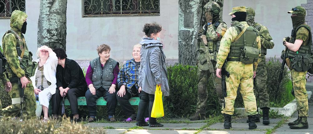 Mai 2022: Ältere Anwohner von Cherson sprechen mit einer Gruppe russischer Soldaten. Der Region Cherson steht ein Referendum bevor.