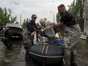 Rettungskräfte evakuieren eine ältere Frau aus einem überfluteten Viertel in Cherson.