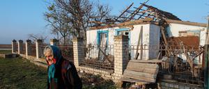 Eine Frau vor einem schwer beschädigten Haus in der Region Cherson