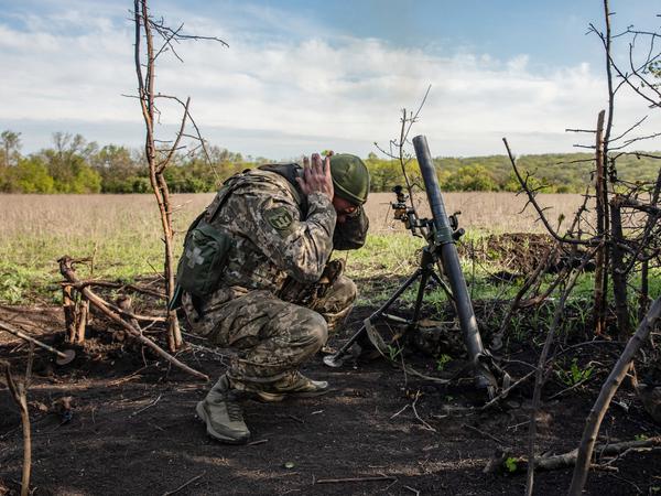 Ein Soldat einer Mörser-Einheit der ukrainischen Streitkräfte hält sich die Ohren zu, während er auf feindliche Stellungen in den Vororten der Stadt Bachmut feuert. 