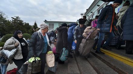 Evakuierte Personen aus Cherson gehen nach ihrer Ankunft am Bahnhof in Dschankoj eine Treppe hoch.