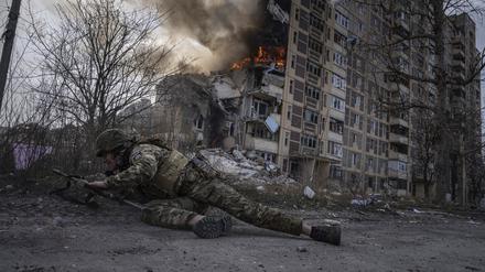 Awdijiwka: Dieses von der Nachrichtenagentur AP am 21.03.2023 zur Verfügung gestellte Foto zeigt einen ukrainischen Polizisten, der vor einem brennenden Gebäude in Deckung geht. 