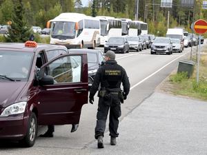 Finnische Grenzbeamte kontrollieren ein russisches Fahrzeug an einer Grenzkontrollstelle.