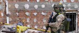 Ein ukrainischer Soldat steht mit seinem Gewehr vor einem zerstörten Gebäude.